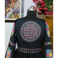 A close-up view of a black traditional Gujarati lehenga choli displayed on a mannequin, featuring intricate mirror work and colorful embroidered patterns on the back and sleeves.

