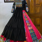 A beautifully designed black and pink traditional Gujarati lehenga choli displayed on a mannequin, featuring intricate mirror work, colorful embroidery, and a flared silhouette with silver and gold border detailing.

