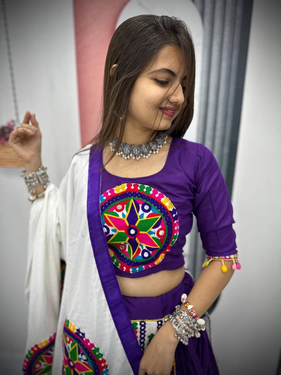 Woman in a purple Gamthi embroidered blouse with mirror work, paired with a white dupatta, styled with silver jewelry.