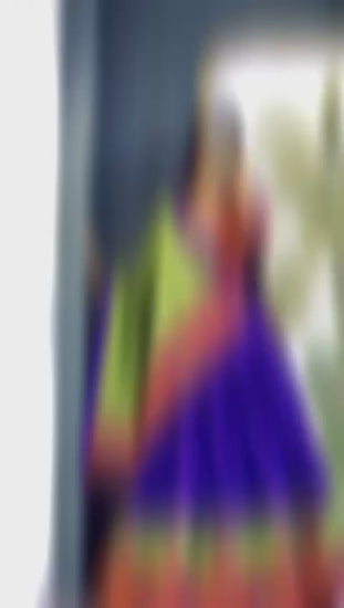 A girl showcasing a colorful lehenga in front of a mirror, wearing a vibrant ensemble with intricate designs.