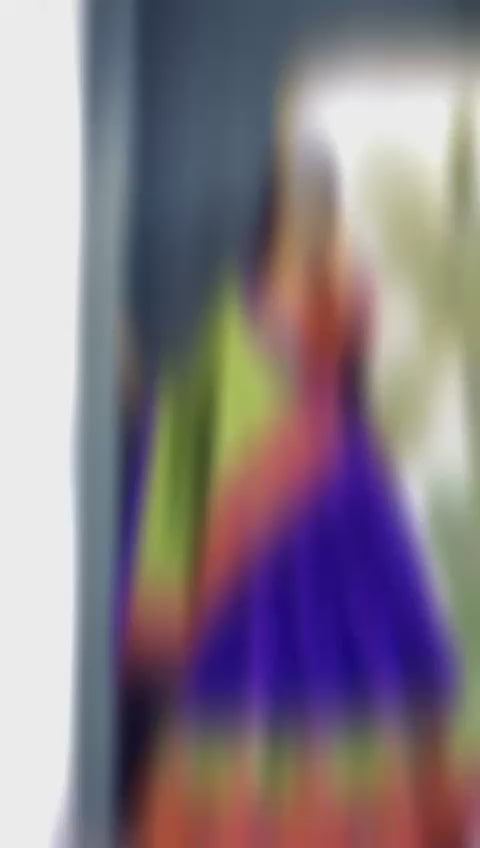 A girl showcasing a colorful lehenga in front of a mirror, wearing a vibrant ensemble with intricate designs.