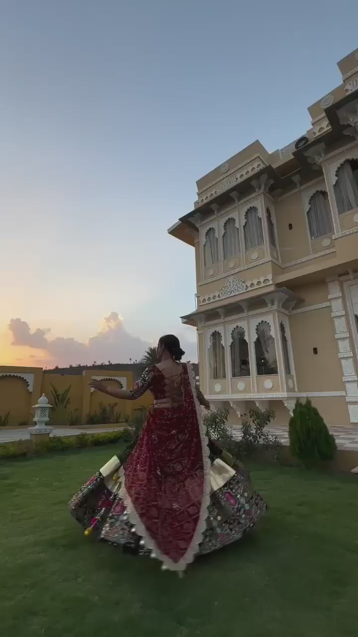 A vibrant traditional Navratri Gujarati lehenga with intricate mirror work and a canvas patta border is showcased. The lehenga features a stunning combination of black, red, and yellow hues with a 4-meter flair. The video captures the detailed embroidery, rich fabric textures, and elegant drape of the outfit, highlighting its festive appeal.