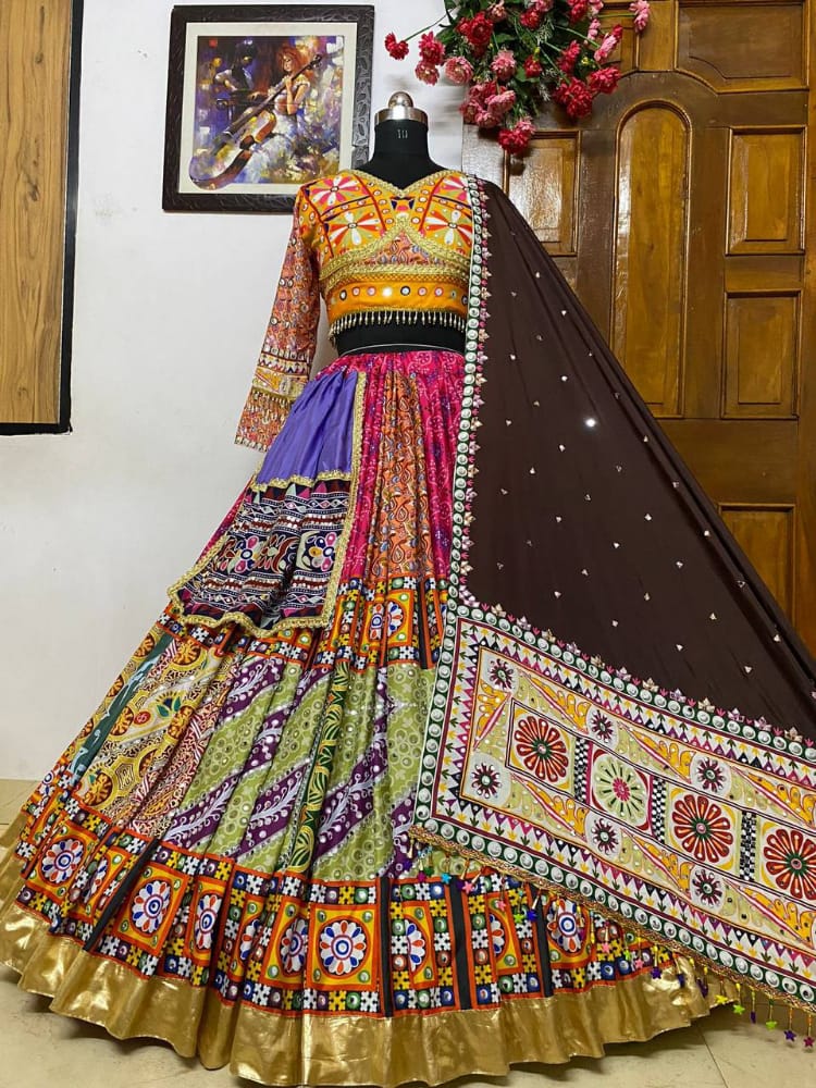A beautifully designed Gujarati-style Lehenga Choli displayed on a mannequin, featuring intricate embroidery, vibrant patchwork, mirror embellishments, and a rich brown dupatta, perfect for Navratri and festive occasions.